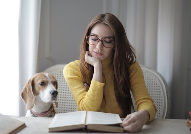 a woman reading a book with a dog