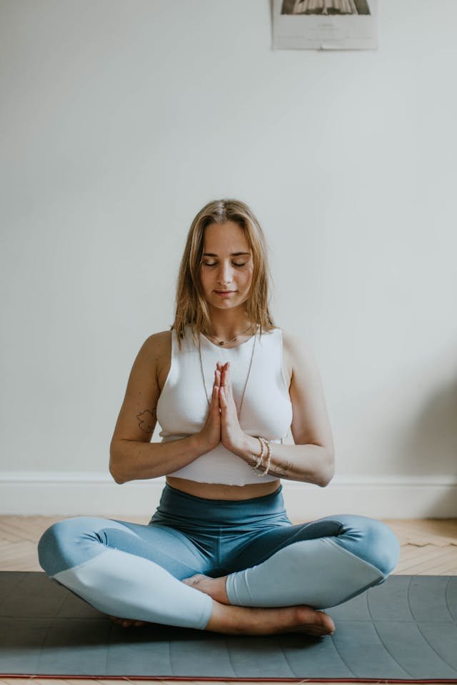 a woman sitting cross legged with hands together in front of her