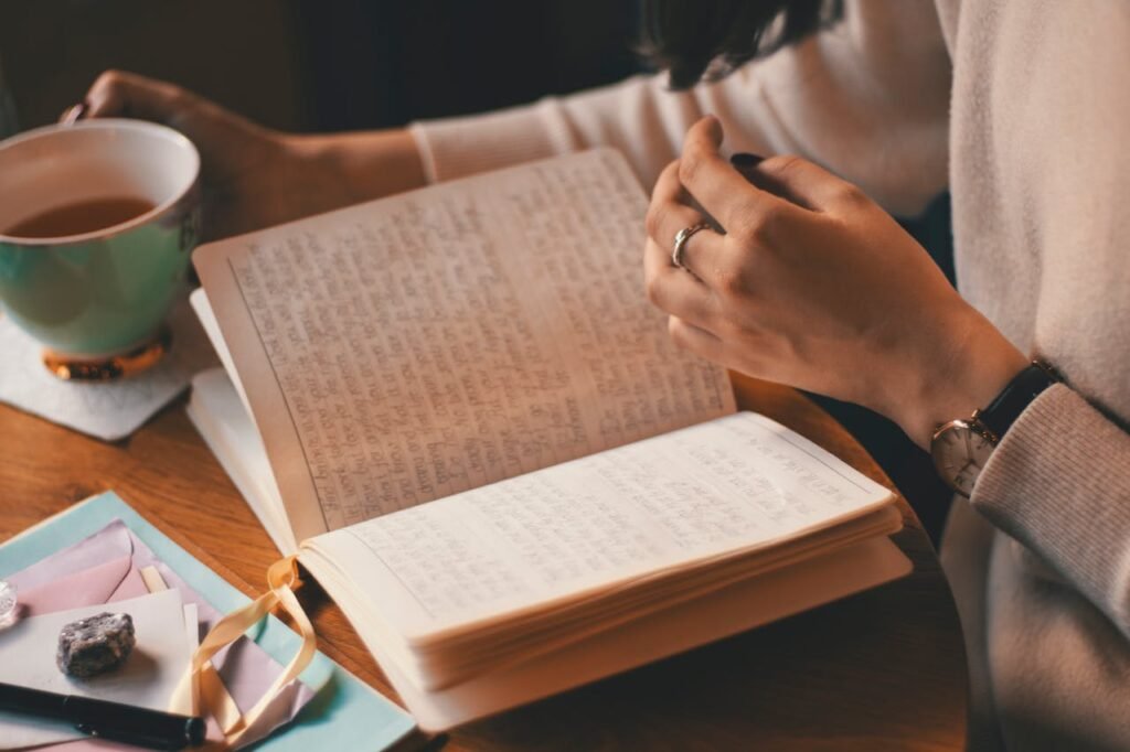 A serene, handcrafted leather-bound journal rests on a wooden table, surrounded by an arrangement of fresh flowers, a calligraphy pen, and a cup of warm tea. Soft natural light filters through a nearby window, casting a warm glow on the scene. The journal's cover features the words "Diário de Gratidão" embossed in an elegant script, inviting the viewer to explore the practice of gratitude. The overall atmosphere is one of mindfulness, reflection, and a sense of tranquility, perfectly capturing the essence of the article's section on "diário de gratidão como fazer". Diario da gratidão