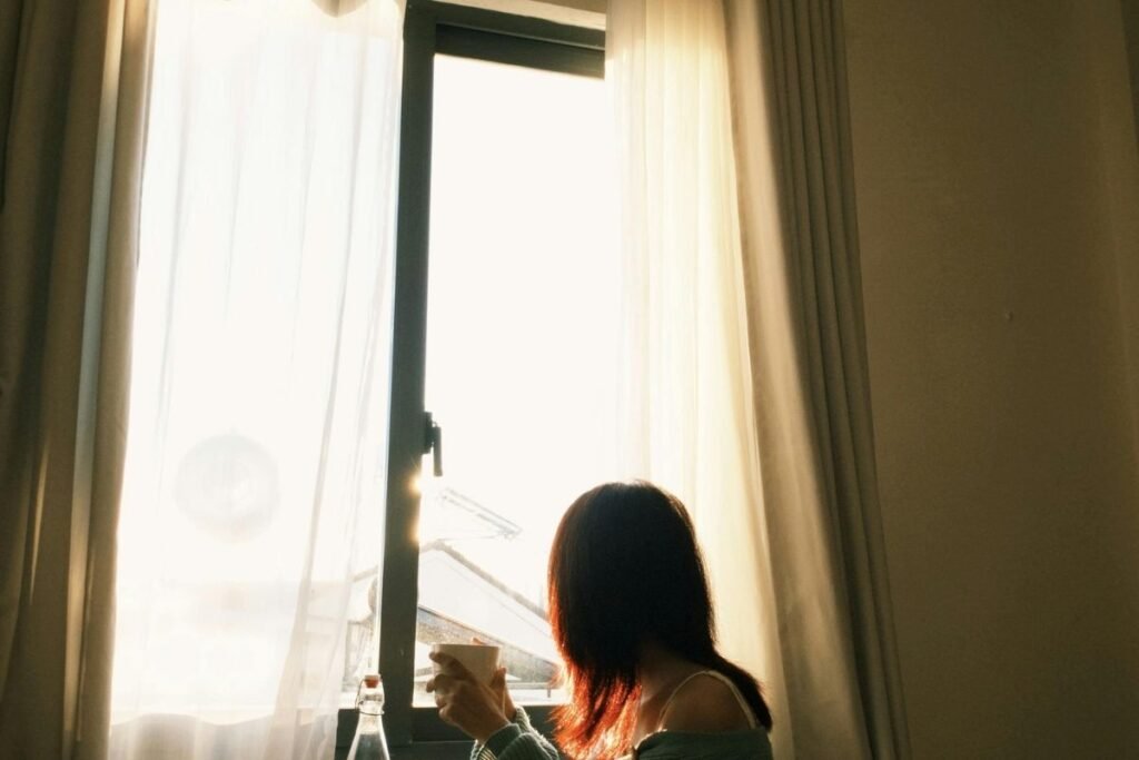 Rotinas de bem-estar: hábitos simples para ansiedade, sono e energia (guia prático) 2 mulher trabalhando e fazendo pausa consciente (olhar pela janela)